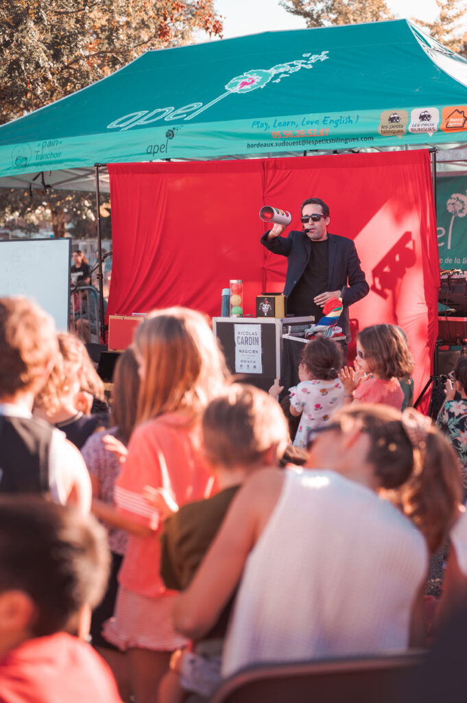 Scène de spectacle de magie avec fond rouge devant un public d'enfants