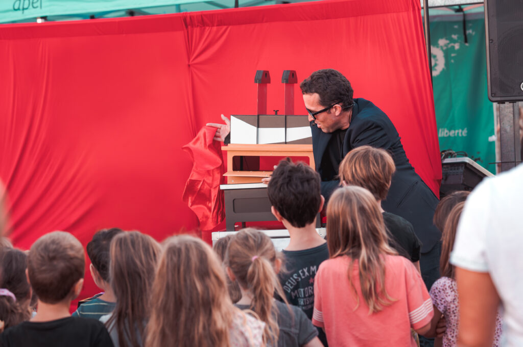 Enfants attentifs devant le magicien Nicolas Cardin sur scène