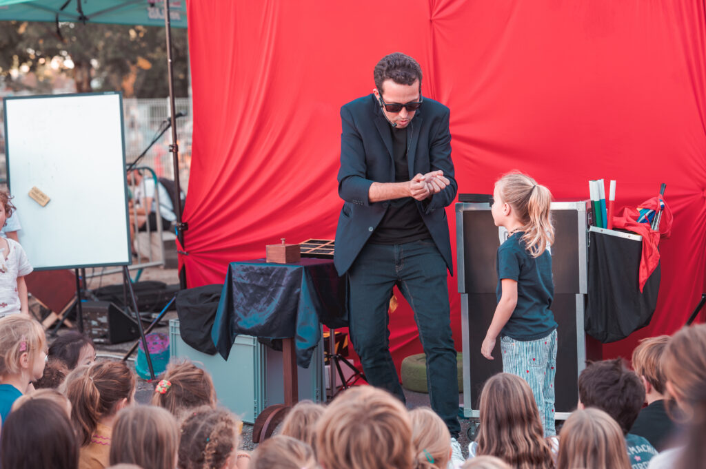 Le magicien Nicolas Cardin avec une enfant volontaire pendant un tour