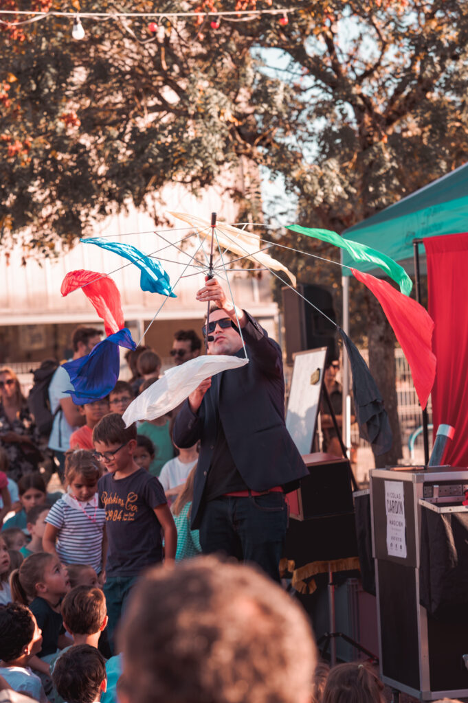 Magicien avec des foulards colorés devant un public d'enfants